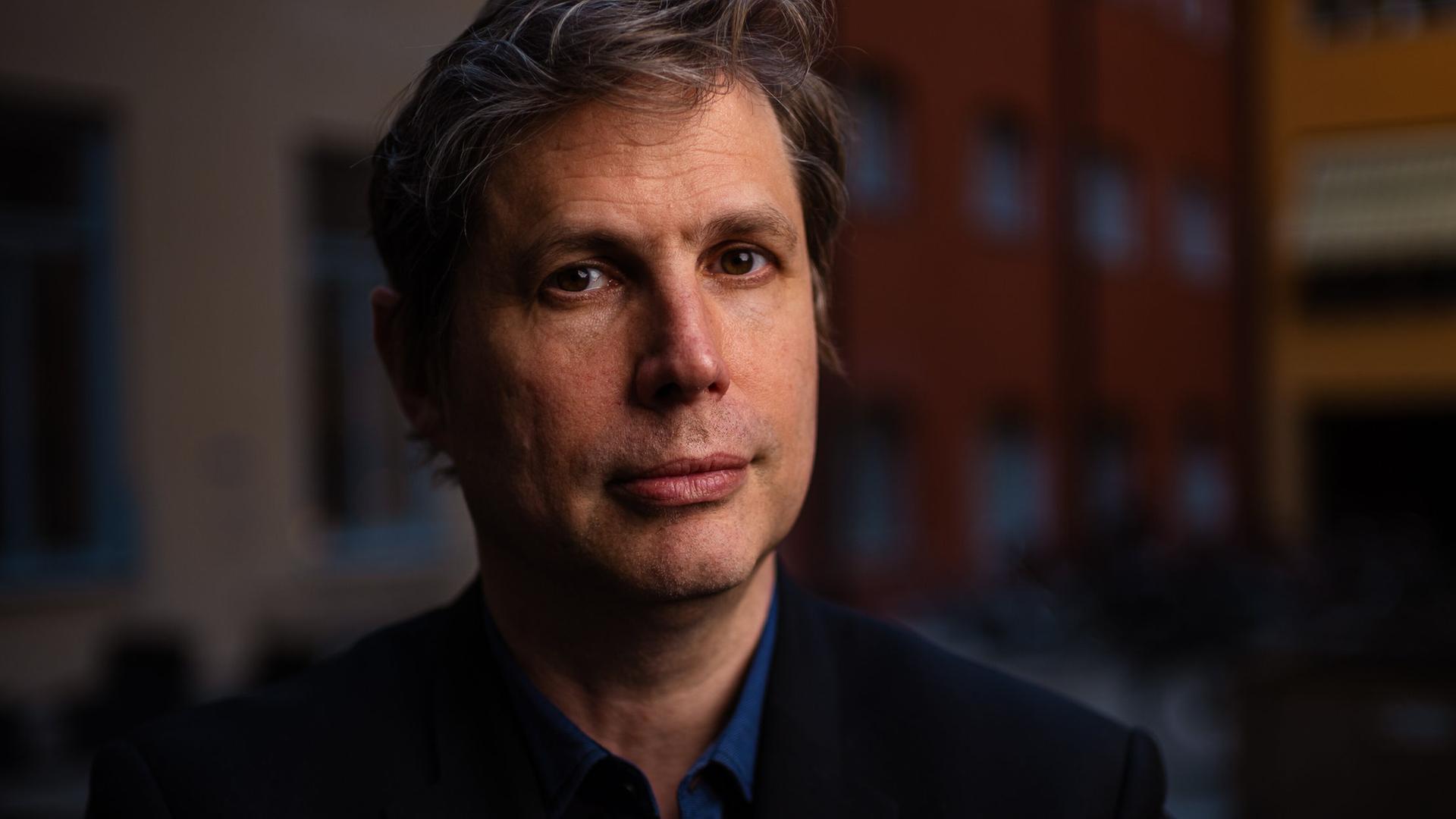 Daniel Kehlmann steht im Abendlicht in einem Innenhof und schaut freundlich in die Kamera. Daniel Kehlmann steht im Abendlicht in einem Innenhof und schaut freundlich in die Kamera.