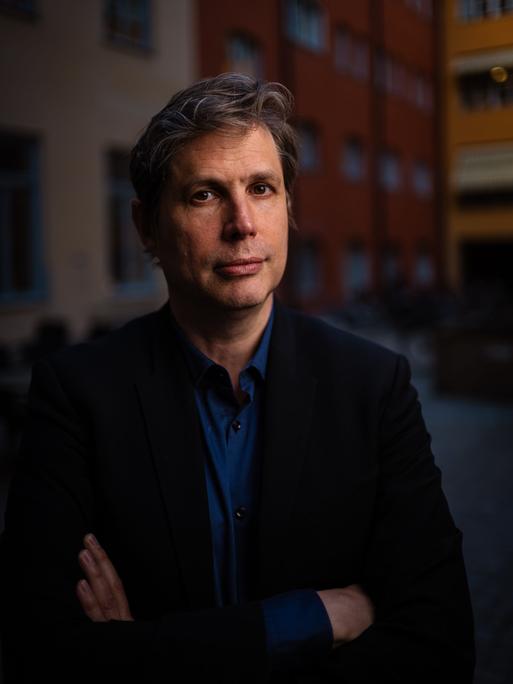 Daniel Kehlmann steht im Abendlicht in einem Innenhof und schaut freundlich in die Kamera.