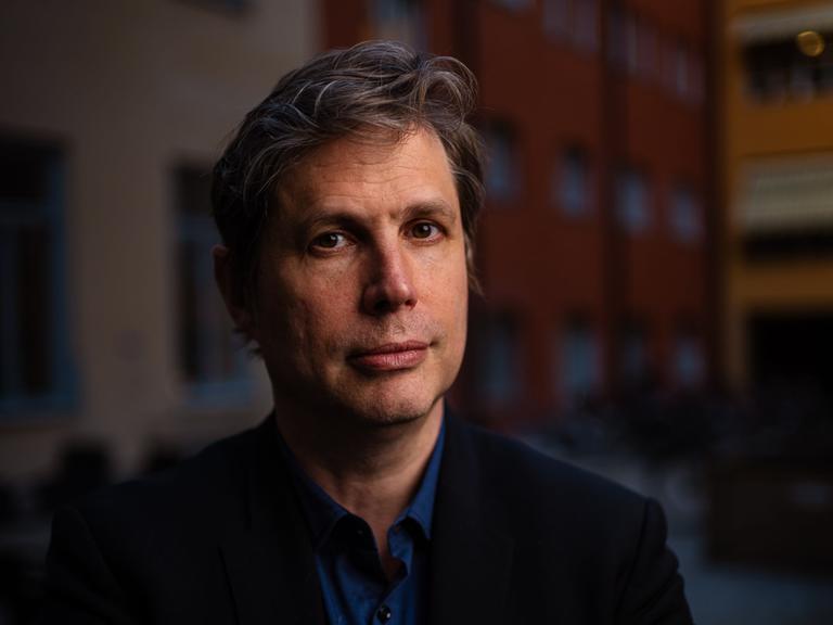 Daniel Kehlmann steht im Abendlicht in einem Innenhof und schaut freundlich in die Kamera.