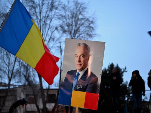 Ein Plakat mit einem Porträt von Călin Georgescu neben einer rumänischen Flagge am 26. Februar 2025. Der rechtsextreme Kandidat wird bei der Wiederholungswahl am 