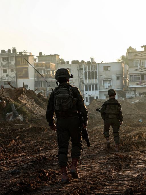 Israelische Soldaten laufen im Gazastreifen an zerstörten Gebäuden vorbei.