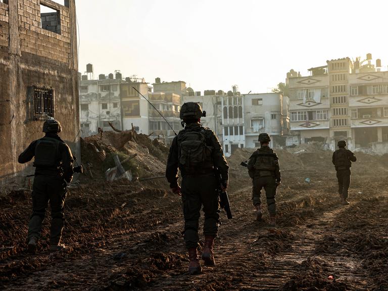 Israelische Soldaten laufen im Gazastreifen an zerstörten Gebäuden vorbei.