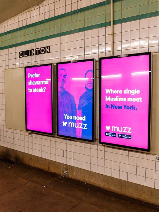 Pinke Plakate mit einem muslimischen Paar und der Aufschrift "Where single Muslims meet in New York" hängen auf einem New Yorker U-Bahnhof.