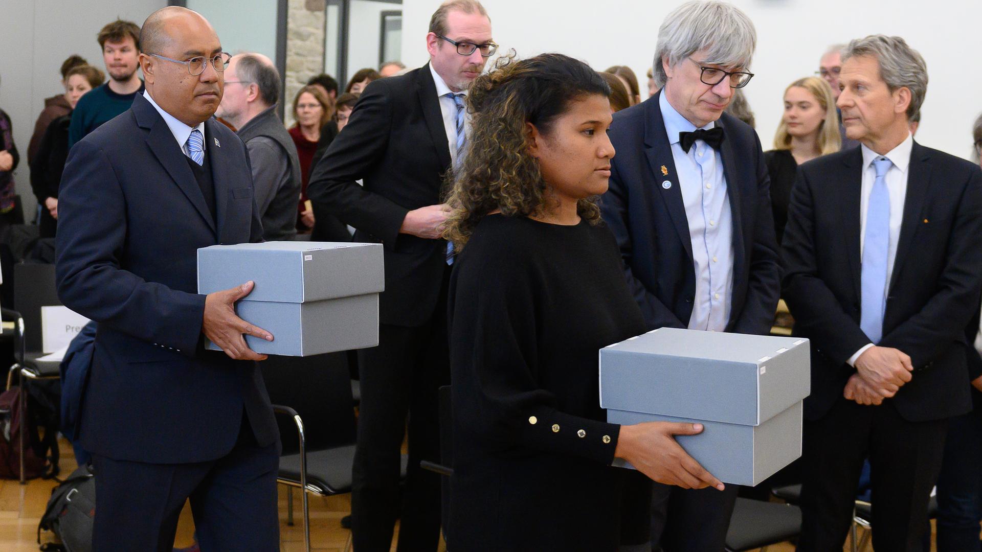 Ribka Kintaro, Vertreterin des Pulo Anna Council, und Ngiraibelas Tmetuchl, Minister für Human Resources, Kultur, Tourismus und Entwicklung der Republik Palau, tragen im Rahmen einer feierlichen Zeremonie der Universität Göttingen Kartons mit menschlichen Gebeinen. Die Universität und die Staatlichen Ethnographischen Sammlungen Sachsen geben menschliche Gebeine an die Republik Palau zurück.
