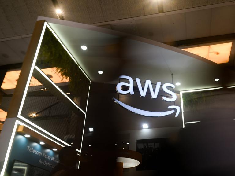 Das Logo AWS, was für Amazon Web Services steht, leuchtet auf einem Messestand