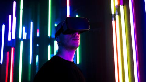 Ein Mann mit VR-Brille vor bunt leuchtenden Lichtern