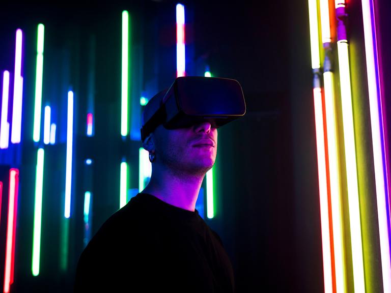 Ein Mann mit VR-Brille vor bunt leuchtenden Lichtern