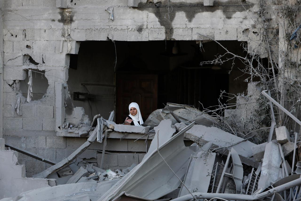 Eine palästinensische Frau schaut aus dem Fester eines beschädigten Hauses im Gazastreifen 
