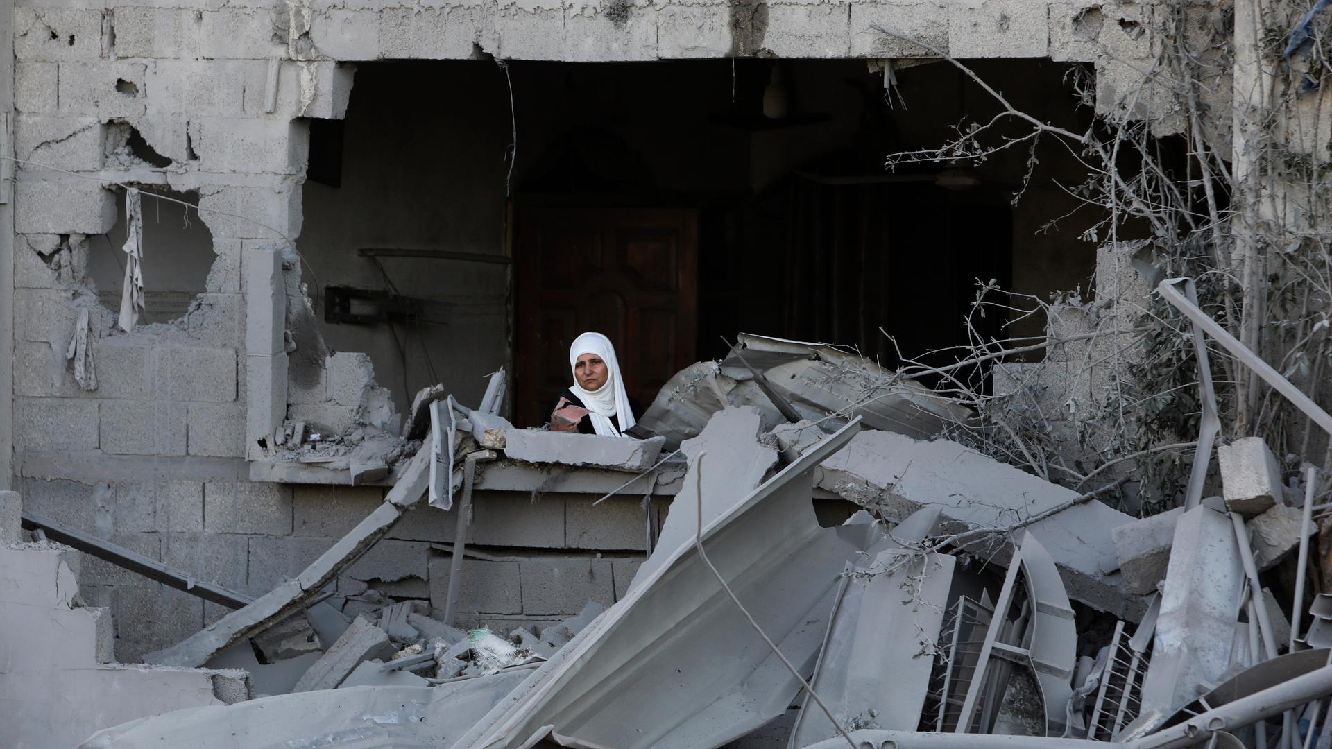 Eine palästinensische Frau schaut aus dem Fester eines beschädigten Hauses im Gazastreifen