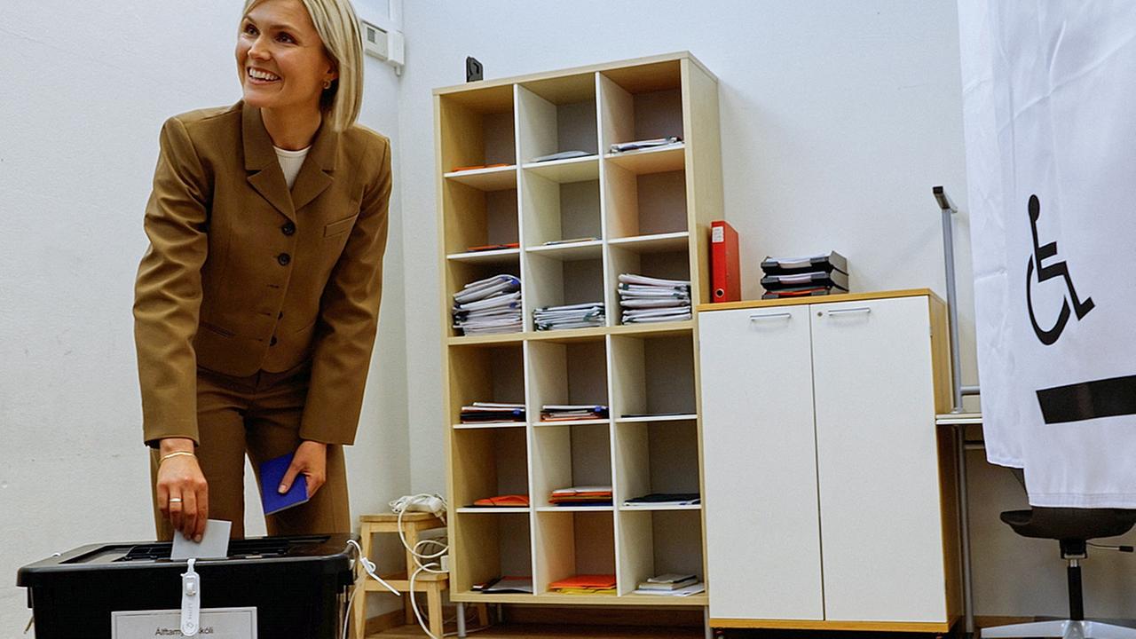 Islands Premierministerin Kristrun Frostadottir bei der Stimmabgabe. Sie beugt sich leicht nach vorne und wirft den Stimmzettel in die Wahlurne.