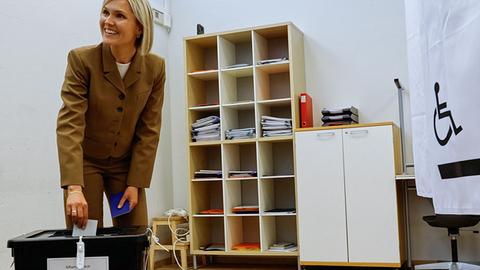 Islands Premierministerin Kristrun Frostadottir bei der Stimmabgabe. Sie beugt sich leicht nach vorne und wirft den Stimmzettel in die Wahlurne.