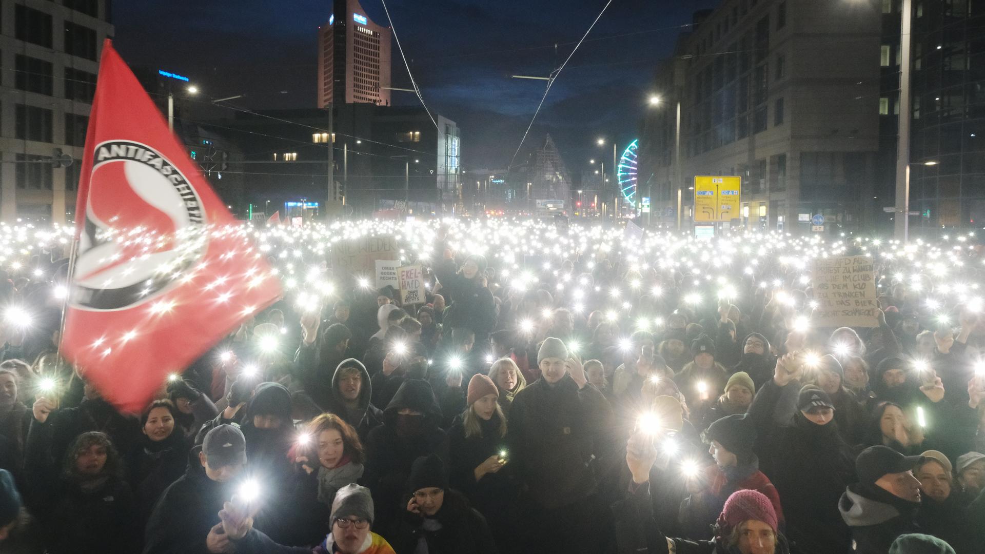 Teilnehmer einer Kundgebung versammeln sich auf dem Johannisplatz und leuchten mit den Taschenlampen ihrer Telefone. In Leipzig hatten sich bei der Demonstration gegen Rassismus, Faschismus, die AfD und für Demokratie nach ersten Polizeiangaben mehr als Zehntausend Menschen versammelt. Der Marktplatz war nach Angaben einer dpa-Reporterin überfüllt, auch in den Seitenstrassen standen die Menschen dicht gedrängt. Die Veranstalter sprachen von mehr als 20 000 Teilnehmern.