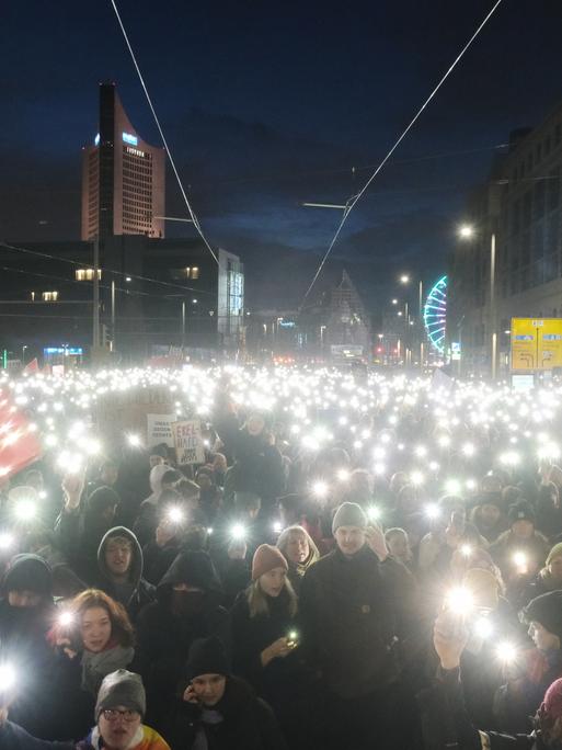 Teilnehmer einer Kundgebung versammeln sich auf dem Johannisplatz und leuchten mit den Taschenlampen ihrer Telefone. In Leipzig hatten sich bei der Demonstration gegen Rassismus, Faschismus, die AfD und für Demokratie nach ersten Polizeiangaben mehr als Zehntausend Menschen versammelt. Der Marktplatz war nach Angaben einer dpa-Reporterin überfüllt, auch in den Seitenstrassen standen die Menschen dicht gedrängt. Die Veranstalter sprachen von mehr als 20 000 Teilnehmern.
