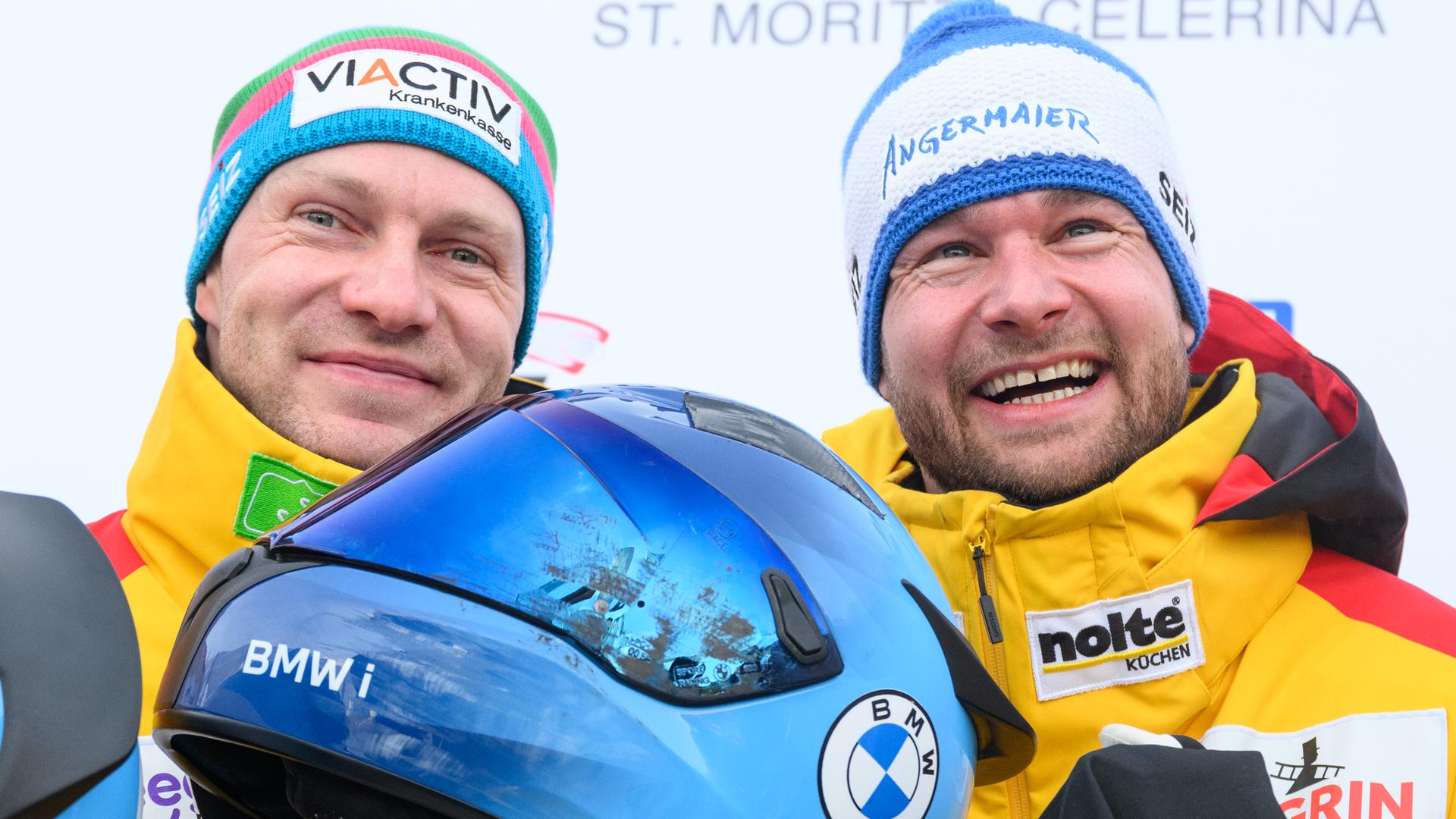 Die Bob-Fahrer Johannes Lochner und Francesco Friedrich lächeln nach einem Rennen in die Kamera.