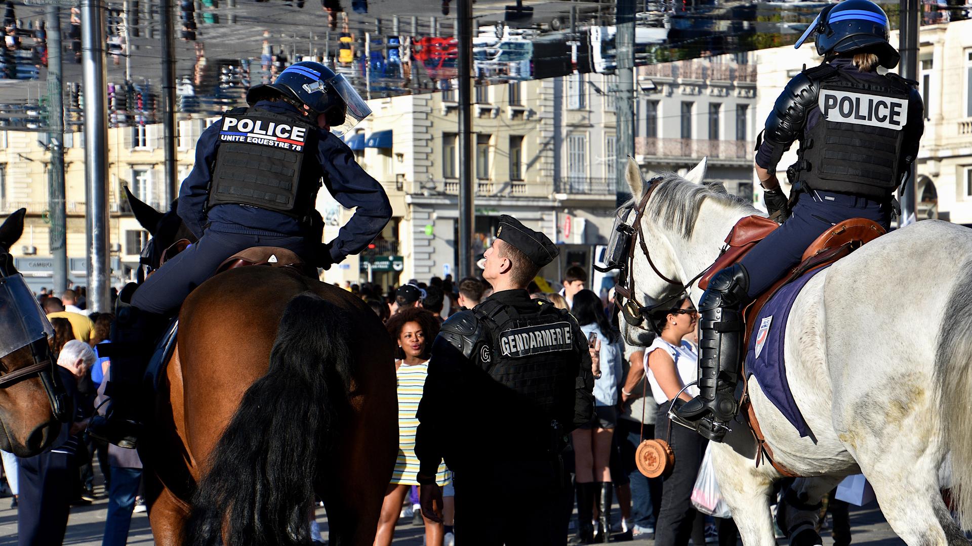 Polizisten in schwerer Schutzausrüstung, teils zu Pferd, in städtischer Umgebung