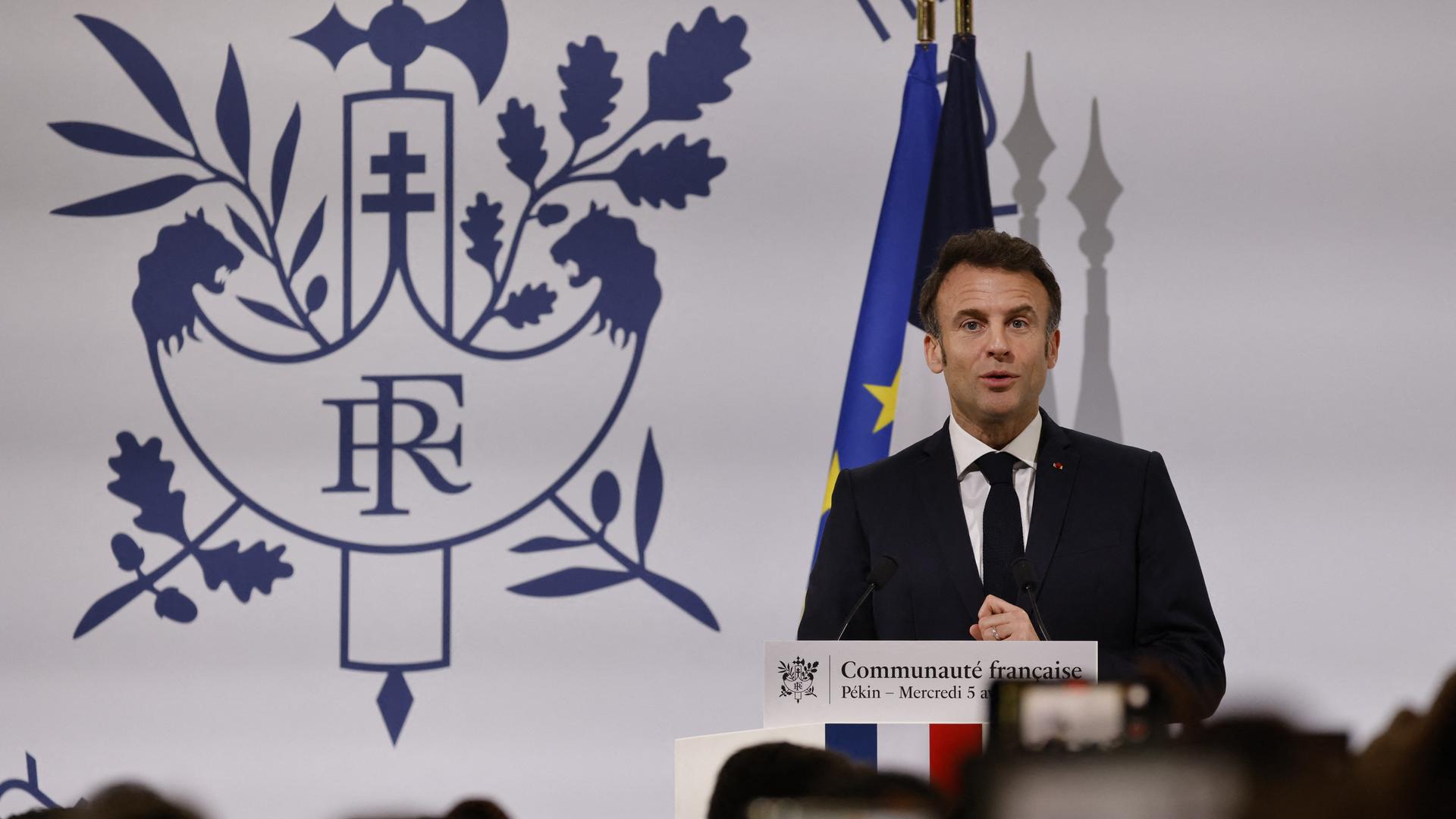 Frankreichs Staatspräsident steht hinter einem Rednerpult. Hinter ihm das Logo der französischen Community in Peking.