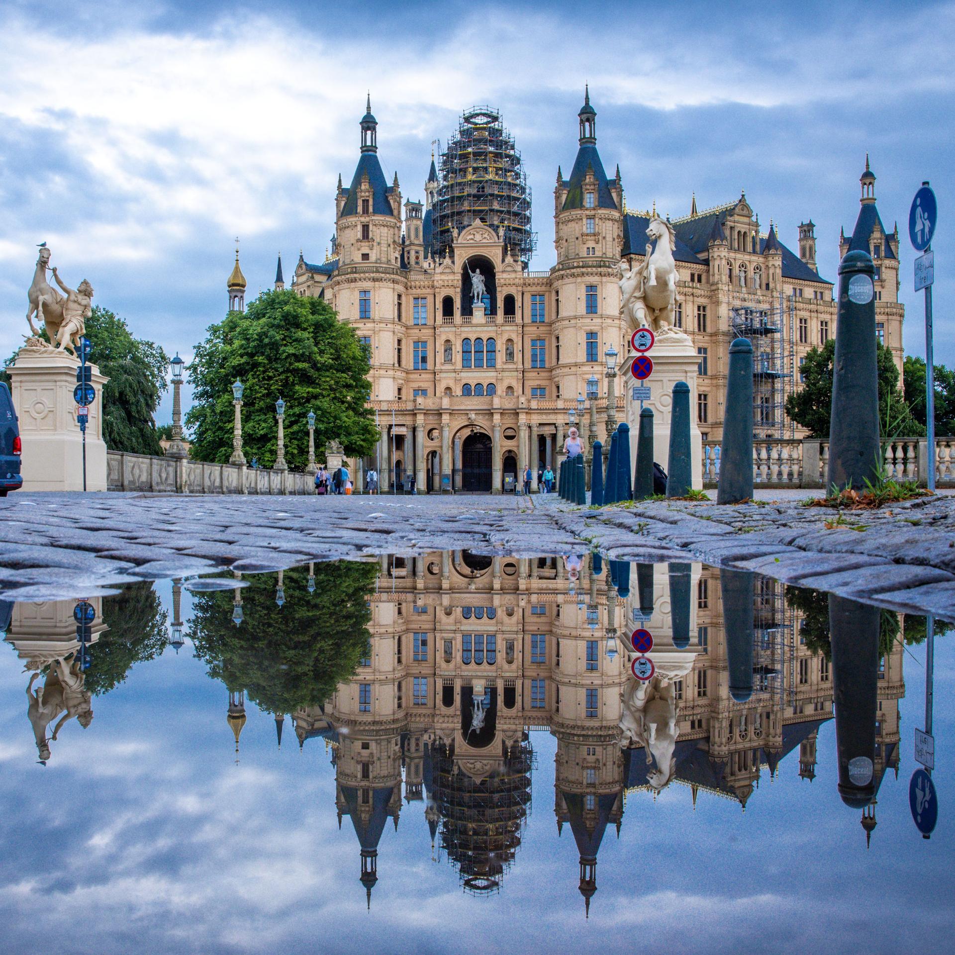 Das Schweriner Schloss spiegelt sich in einer Pfütze. 