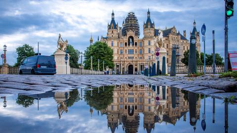 Das Schweriner Schloss spiegelt sich in einer Pfütze. 