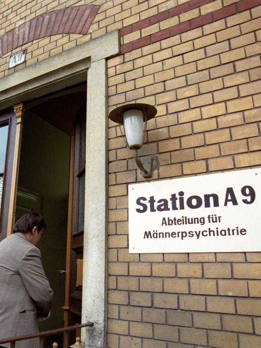 Neben der Eingangstür eines Backsteingebäudes hängt ein Schild mit der Aufrschrift "Station A9 - Abteilung für Männerpsychiatrie".