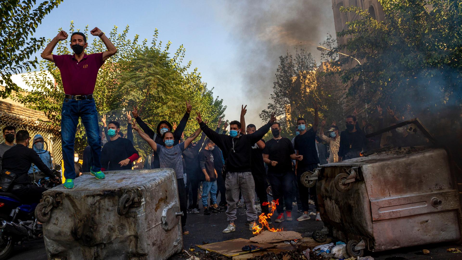Iraner, die in Teheran gegen das Regime protestieren. Sie heben die Hände hoch und blockieren eine Straße.