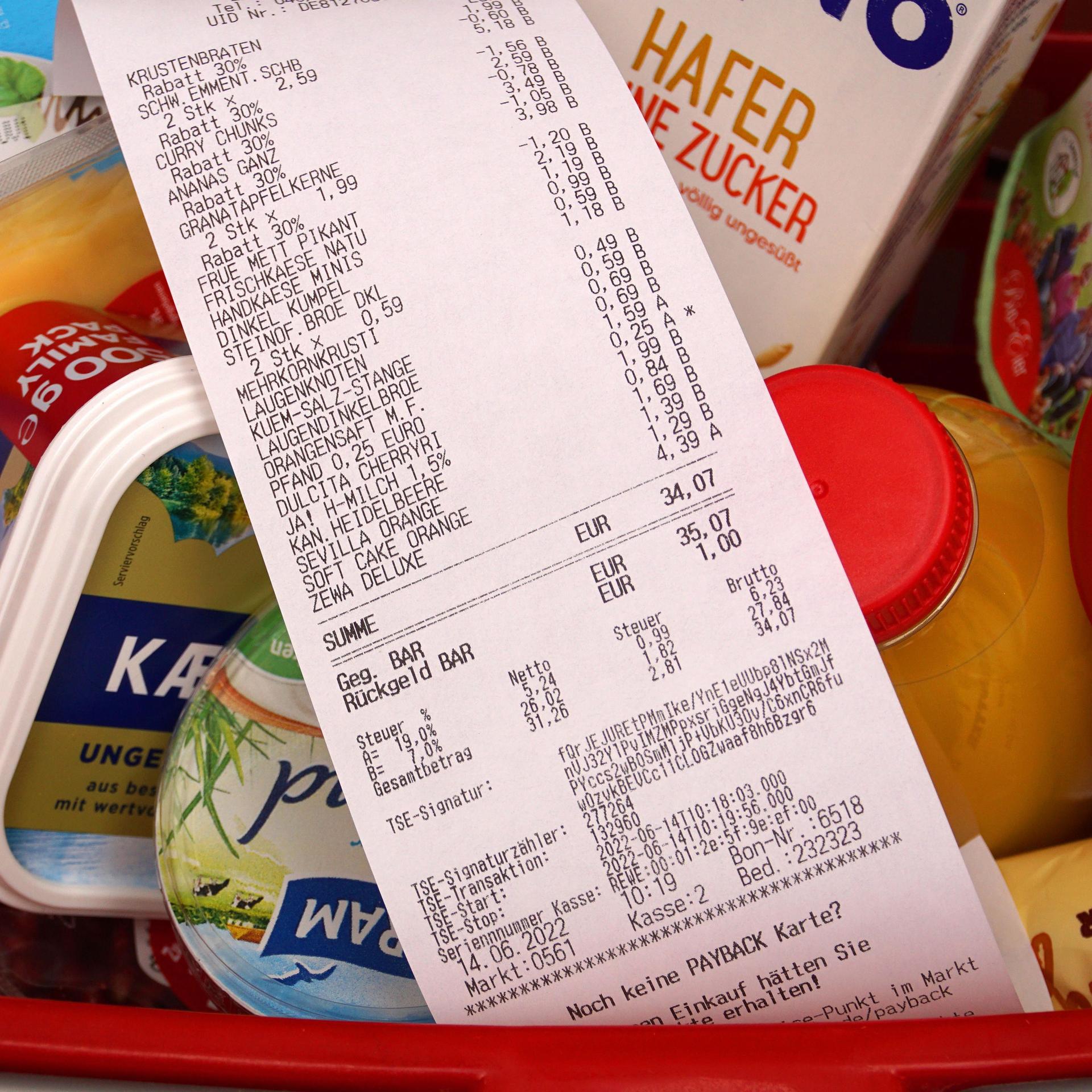 In einem Einkaufskorb lieben viele Lebensmittel. Darauf liegt eine Quittung.