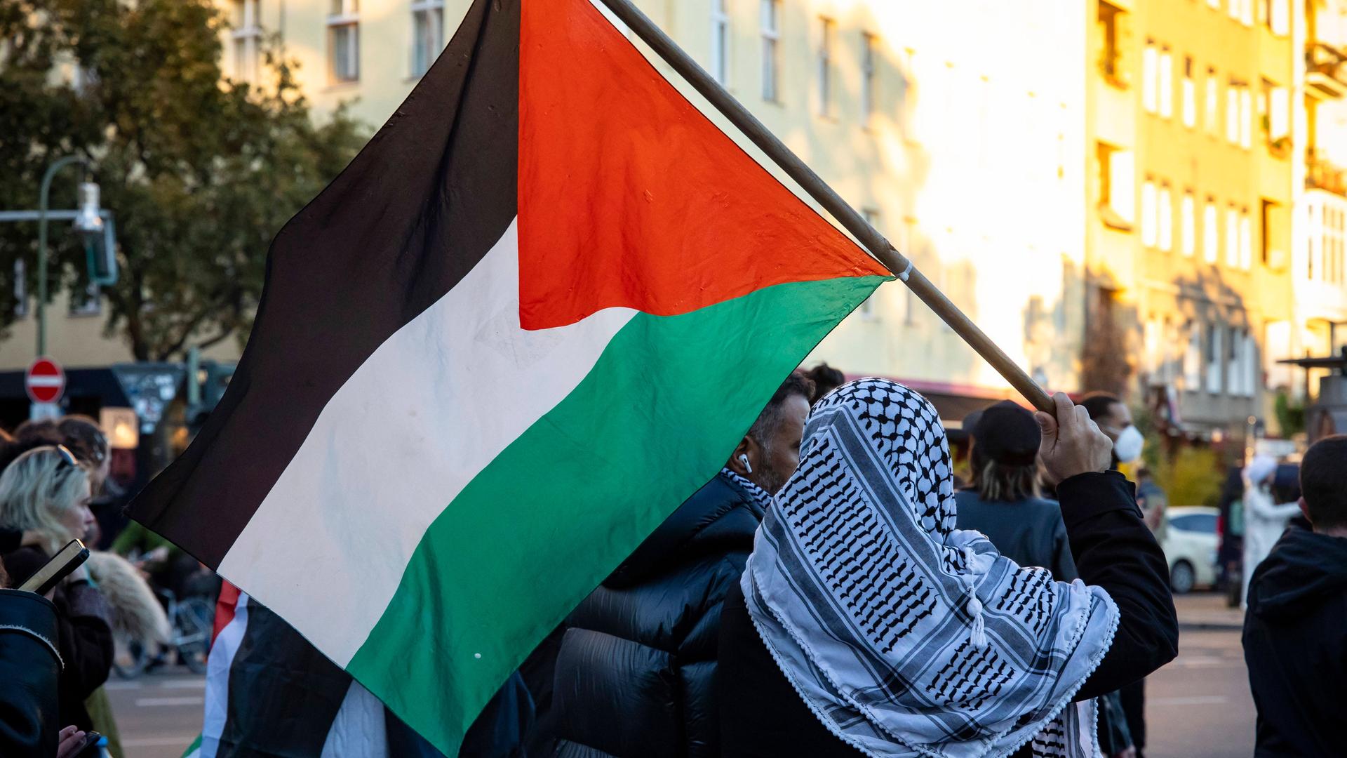Ein Mann mit Palästinenser-Tuch und -Flagge auf einer Solidaritäts-Demonstration mit Palästina in Berlin Kreuzberg am 21. Oktober 2023.