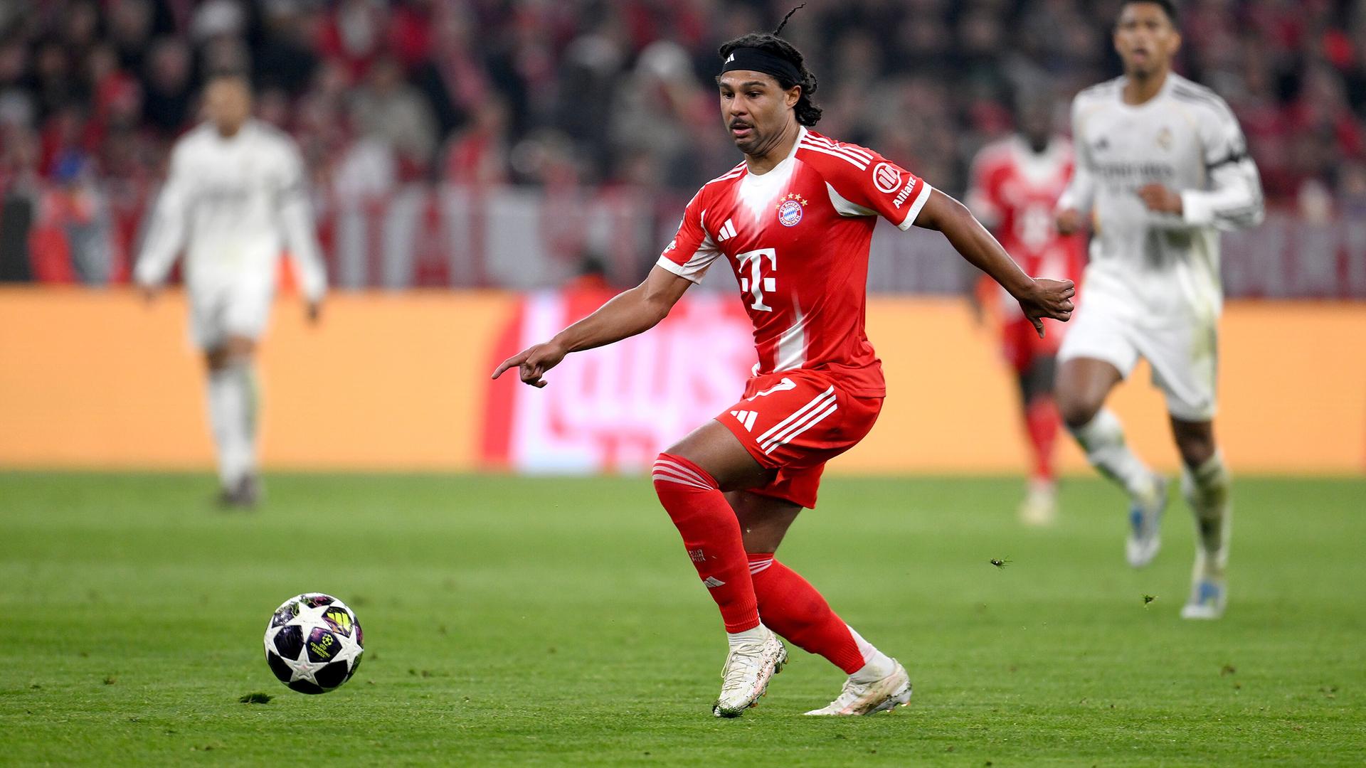 Gnabry geht im roten Trikot des FC Bayern München dem Ball hinterher. Im Hintergrund laufen Spieler von Real Madrid.