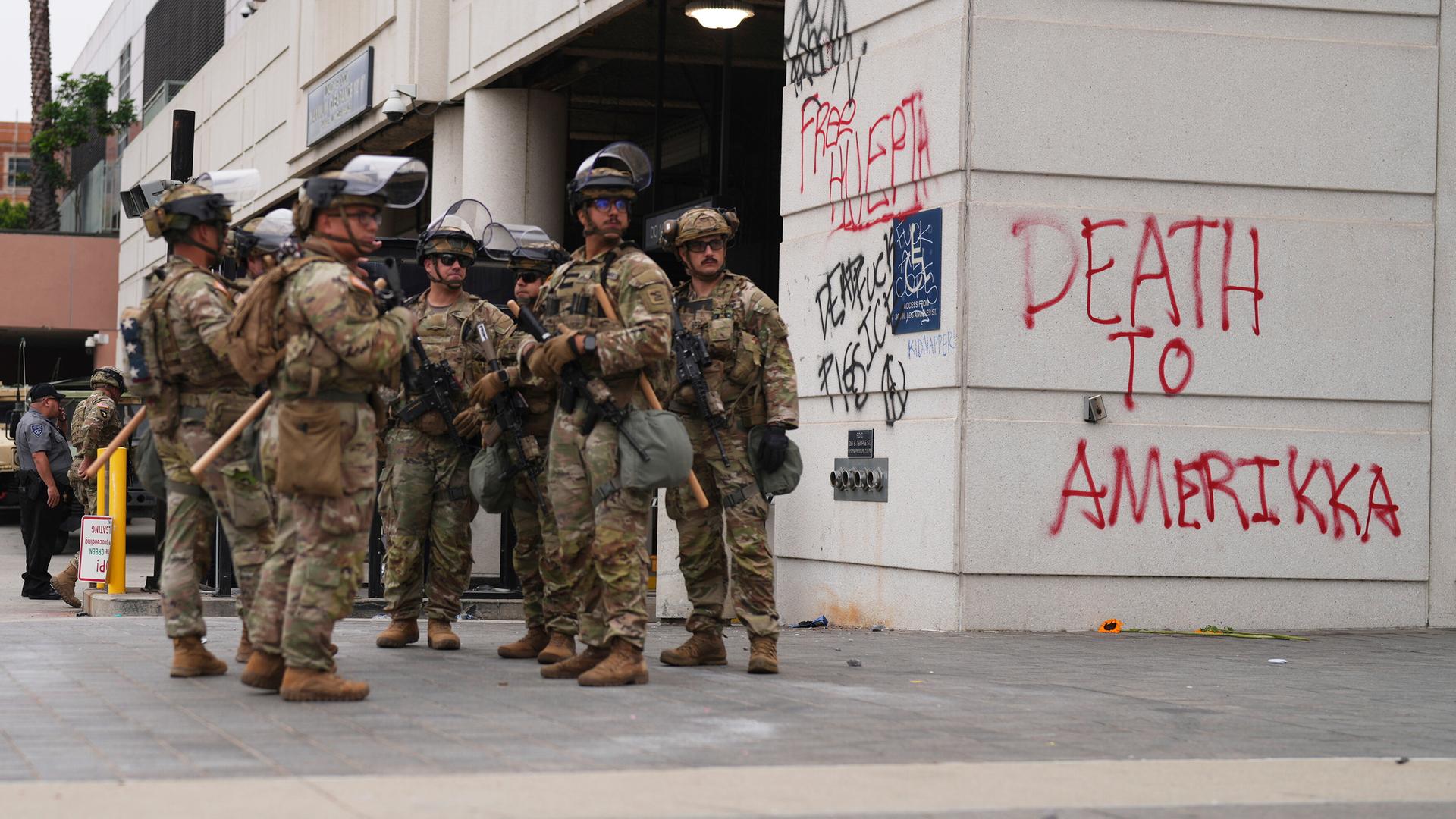 Einsatzkräfte der Nationalgarde stehen neben einem Gebäude, auf dem "Tod für Amerika" an die Wand geschmiert wurde.