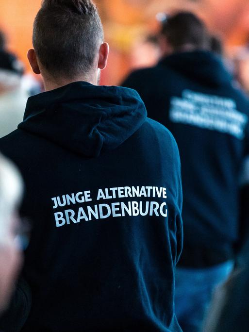 Teilnehmer einer Wahlkampfveranstaltung tragen Kleidung mit der Aufschrift "Junge Alternative Brandenburg".