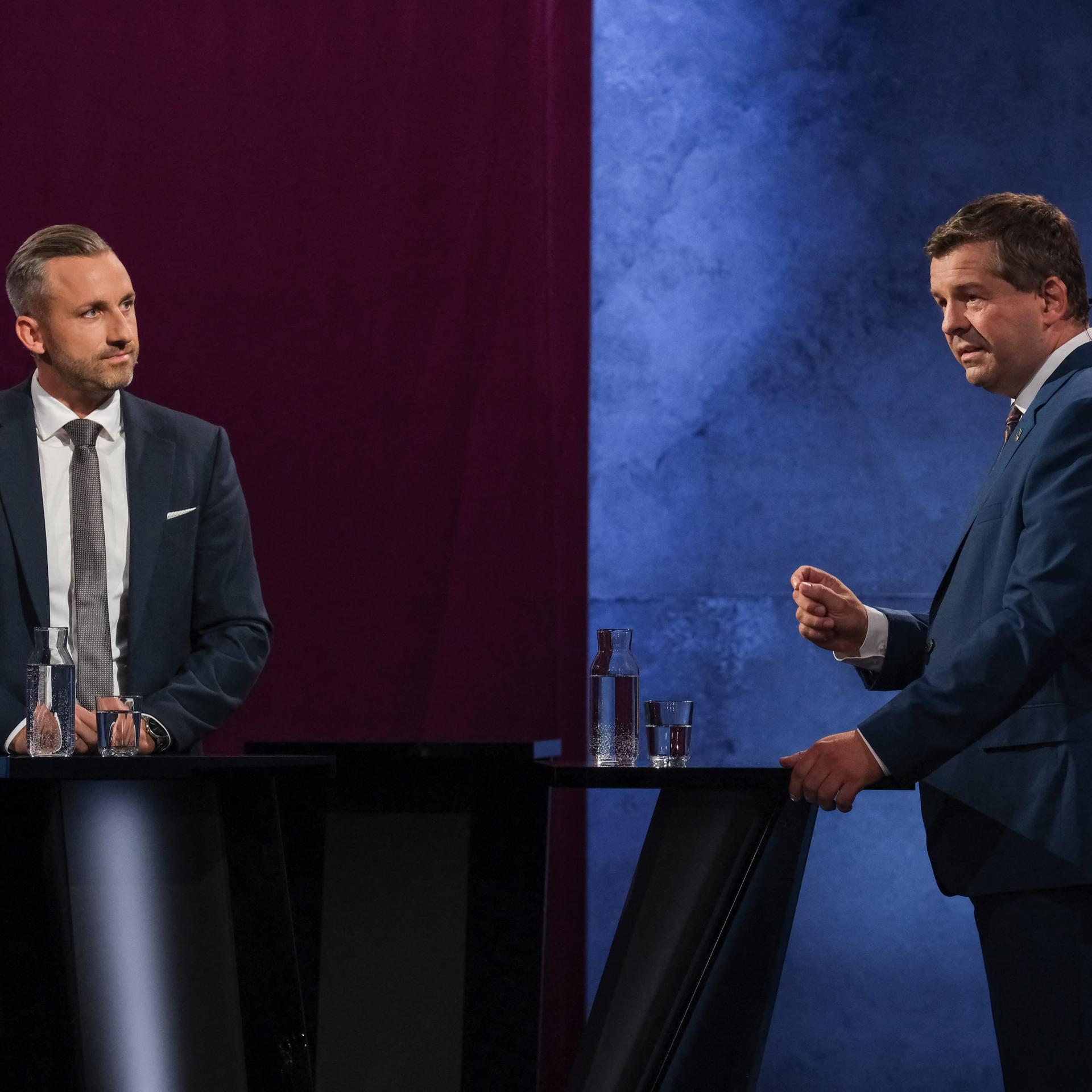 Das Bild zeigt eine Situation aus der Sendung des MDR. Siegmund und Schulze stehen an Redepulten. Schulze spricht und gestikuliert mit einer Hand, Siegmund schaut zu ihm herüber.