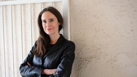 Porträtfoto von Tanja Kinkel. Sie lehnt mit verschrenkten Armen an einer Hauswand mit Toreinfahrt. Porträtfoto von Tanja Kinkel. Sie lehnt mit verschrenkten Armen an einer Hauswand mit Toreinfahrt.