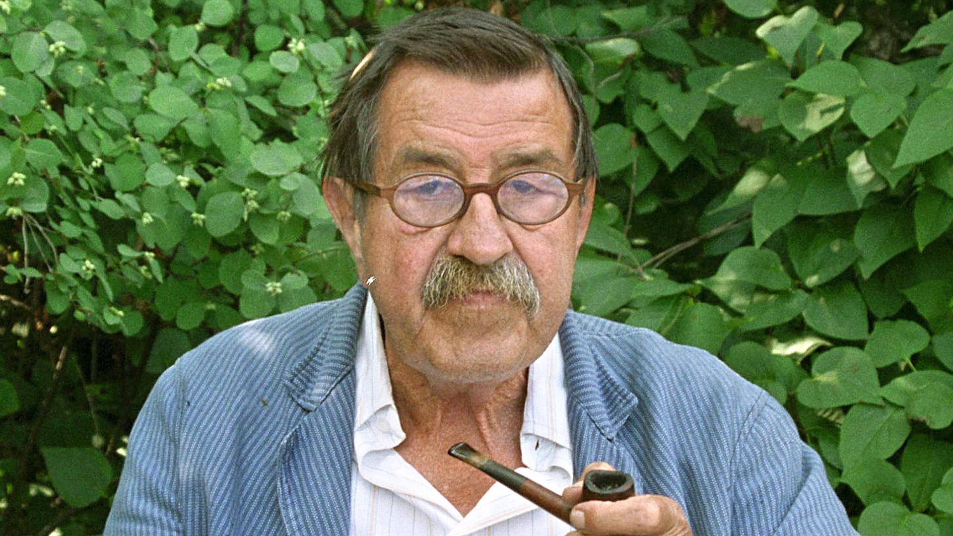 Günter Grass sitzt mit Pfeife vor Blätterwerk Günter Grass sitzt mit Pfeife vor Blätterwerk