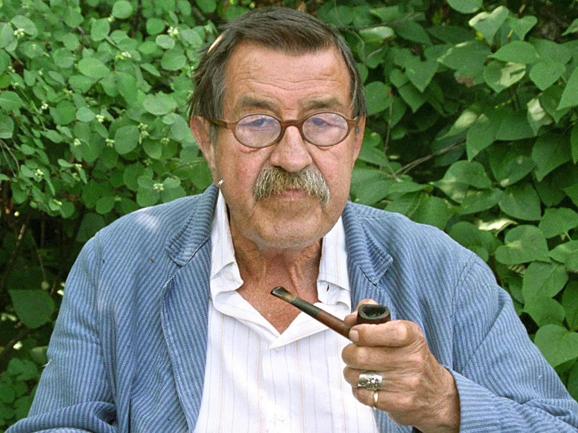 Günter Grass sitzt mit Pfeife vor Blätterwerk Günter Grass sitzt mit Pfeife vor Blätterwerk