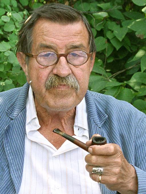 Günter Grass sitzt mit Pfeife vor Blätterwerk