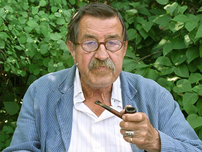 Günter Grass sitzt mit Pfeife vor Blätterwerk