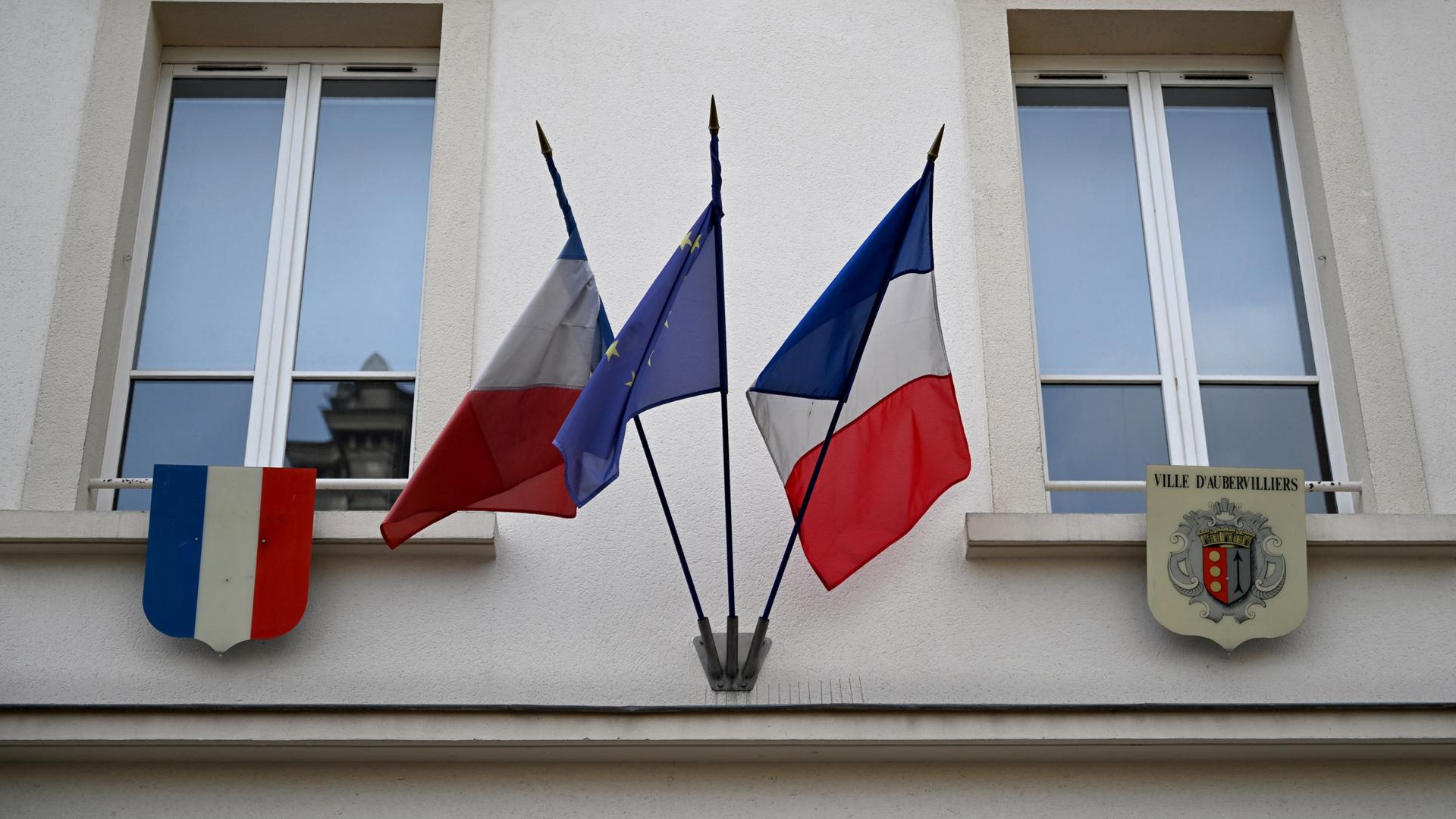 Die französische und die europäische Flagge sowie das Stadtwappen (R) wehen über dem Eingang des Rathauses von Aubervilliers.