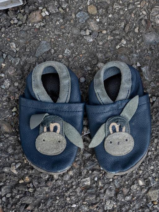 Zwei Paar Kinderschuhe aus einer Spendenkiste für Bedürftige stehen auf dem Asphalt
