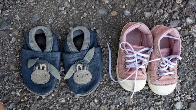 Zwei Paar Kinderschuhe aus einer Spendenkiste für Bedürftige stehen auf dem Asphalt