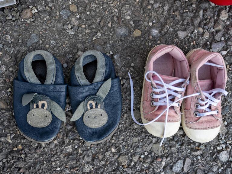Zwei Paar Kinderschuhe aus einer Spendenkiste für Bedürftige stehen auf dem Asphalt