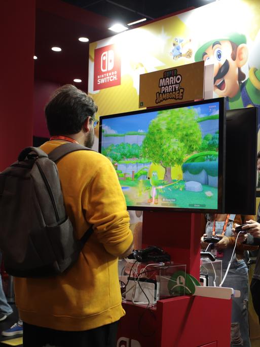 Ein Mann steht vor einem Bildschirm und spielt ein Super-Mario-Spiel von Nintendo Ein Mann steht vor einem Bildschirm und spielt ein Super-Mario-Spiel von Nintendo