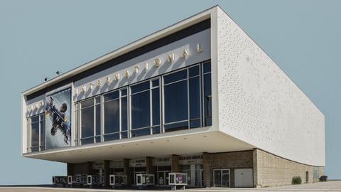Die Fotografie der Künstlerin Sarah Eick zeigt das Berliner Kino International als Einzelgebäude vor einem blassblauen Hintergrund.