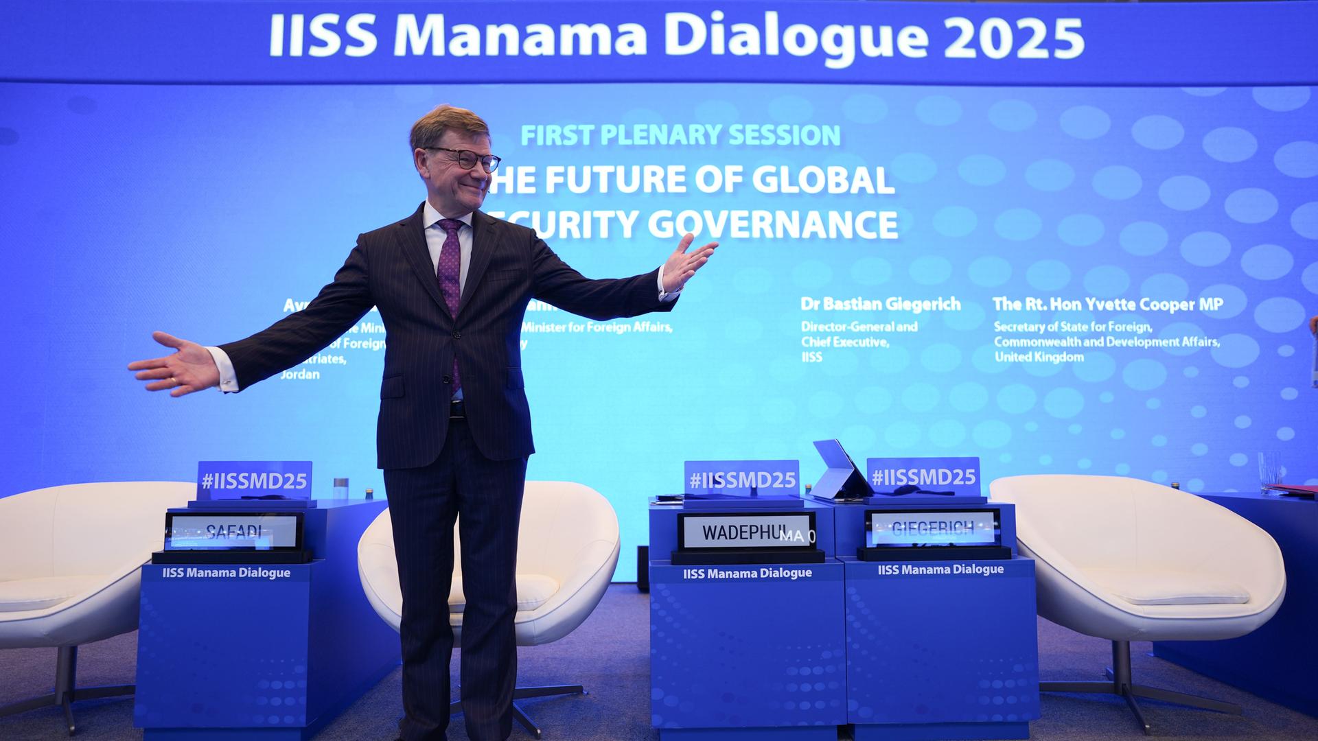 Zu Beginn einer Sicherheitskonferenz in Bahrain steht Außenminister Johann Wadephul mit ausgebreiteten Armen auf einer Bühne. 