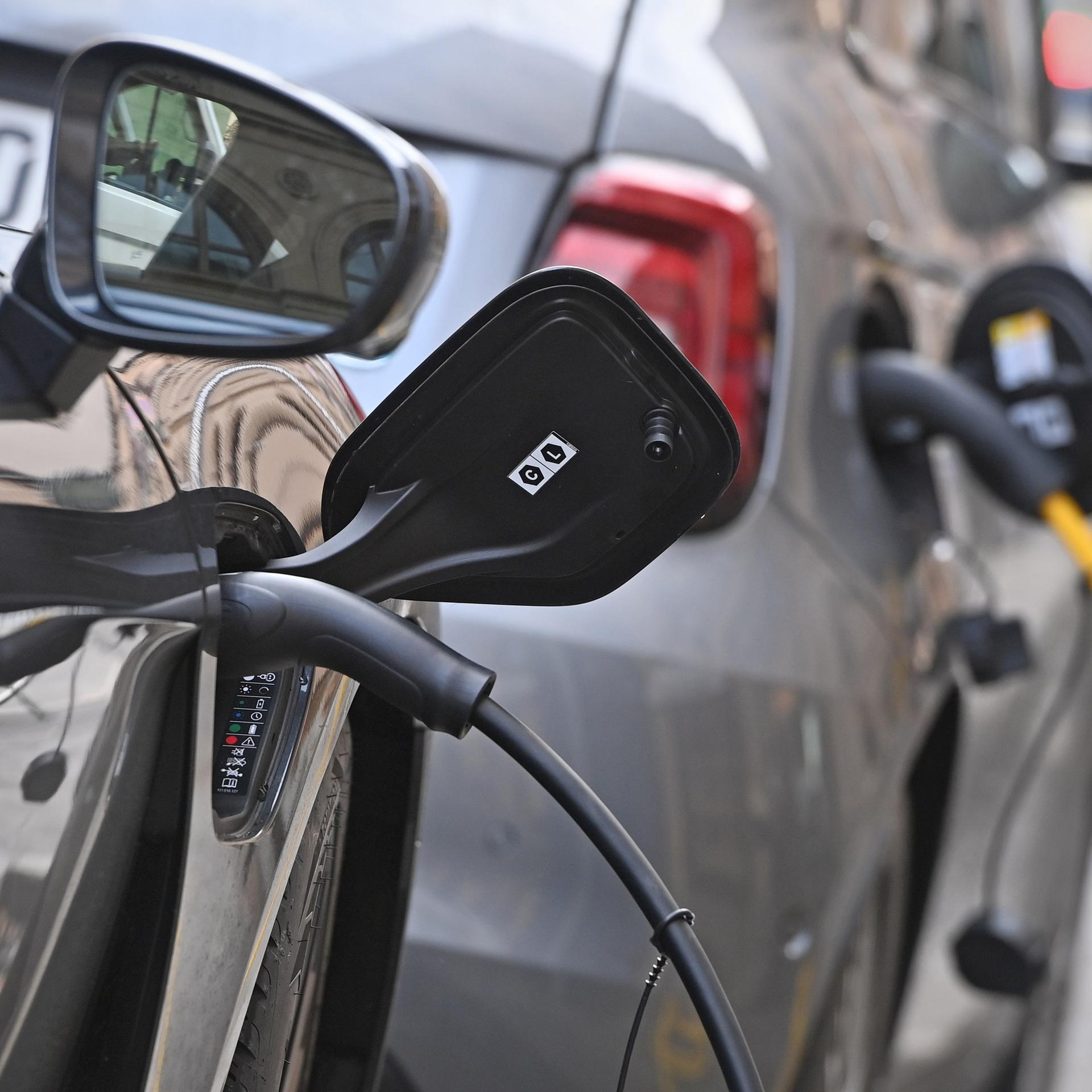 E-Auto am Strassenrand in Muenchen wird geladen, Stecker waehrend dem Ladevorgang an einem E-Auto