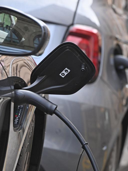 E-Auto am Strassenrand in Muenchen wird geladen, Stecker waehrend dem Ladevorgang an einem E-Auto
