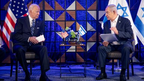 Joe Biden und Benjamin Netanjahu sitzen während eines Gesrpächs in einem Raum beieinander, im Hintgergrund sind eine amerikanische und eine israelische Flagge zu sehen.