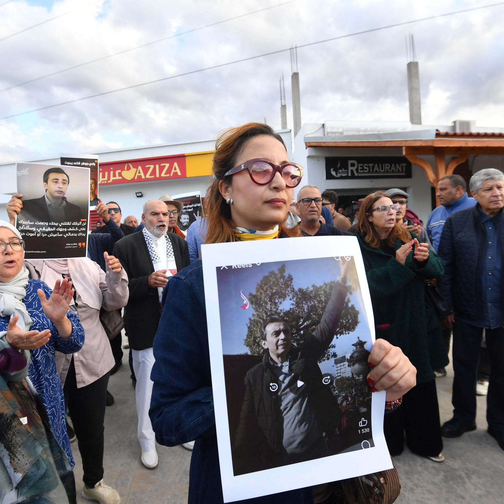 Die tunesische Journalistin und Menschenrechtsaktivistin Chaima Issa hält das Porträt des inhaftierten Oppositionellen Jawhar Ben Mbarek bei einer Demonstration im November 2025. 