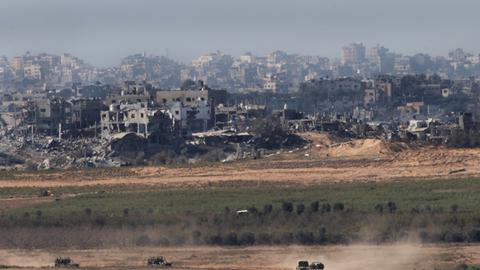 Blick von Israel auf den nördlichen Gazastreifen; im Hintergrund zerstörte Häuser, vorne fahren israelische Militärfahrzeuge (16.11.2023)