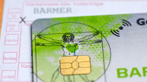 Eine elektronische Gesundheitskarte mit Chip, im Hintergrund ein ärztliches Dokument.