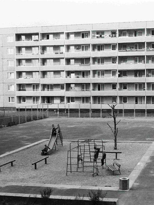 Schwarz-Weiß-Bild eines Spielplatzes aus der Vogelperspektive inmitten von Plattenbauten in der Joseph-Orlopp-Straße in Berlin-Lichtenberg zu DDR-Zeiten