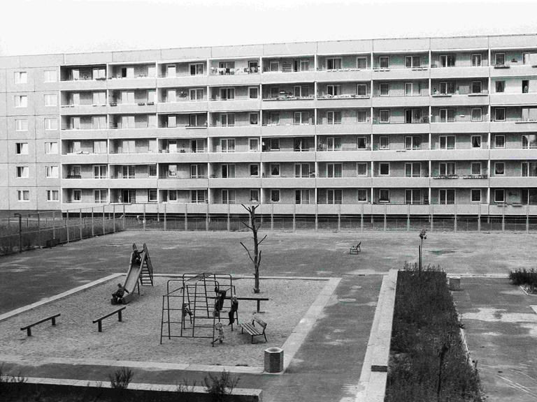 Schwarz-Weiß-Bild eines Spielplatzes aus der Vogelperspektive inmitten von Plattenbauten in der Joseph-Orlopp-Straße in Berlin-Lichtenberg zu DDR-Zeiten